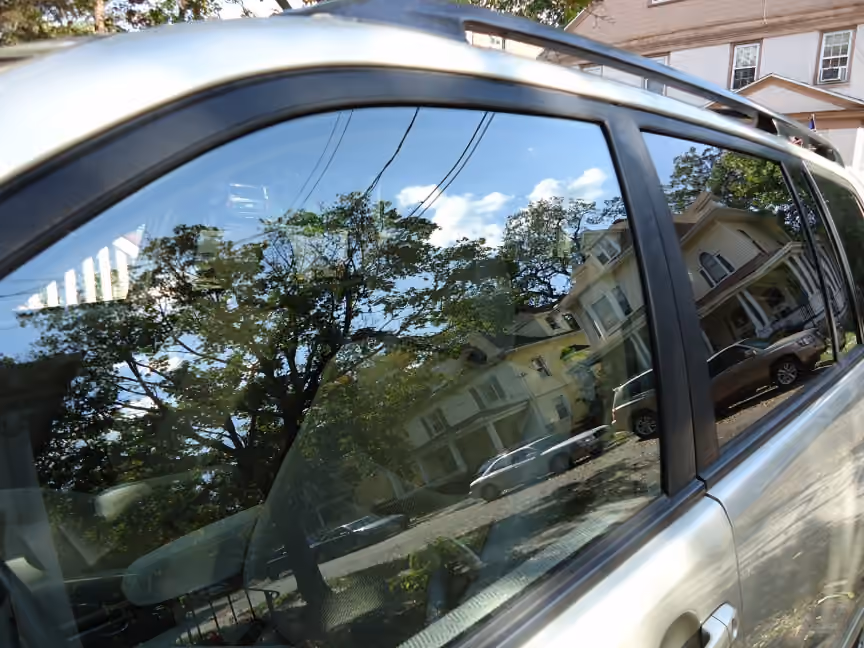 Végétation et bâtiments reflétés dans la vitre d’une voiture Végétation et bâtiments reflétés dans la vitre d’une voiture.