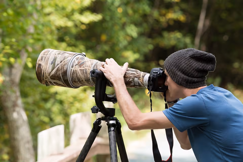 Photographe utilisant un appareil monté sur trépied en extérieur Photographe utilisant un appareil monté sur trépied en extérieur.
